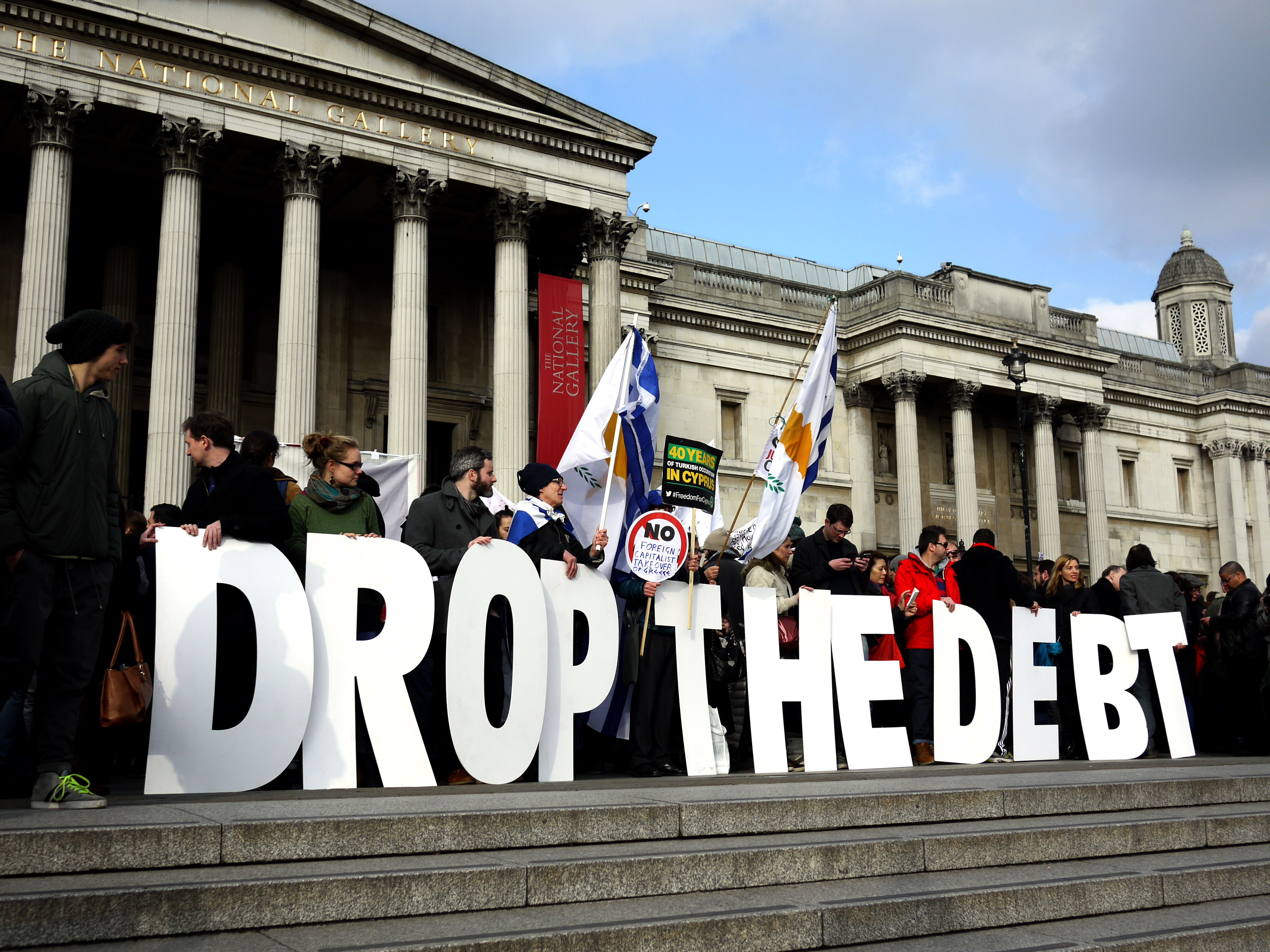 “Let Greece Breathe,” London, Feb 15, 2015. People gather around large cut-out letters that spell out “DROP THE DEPT” in Trafalgar Square, Greece