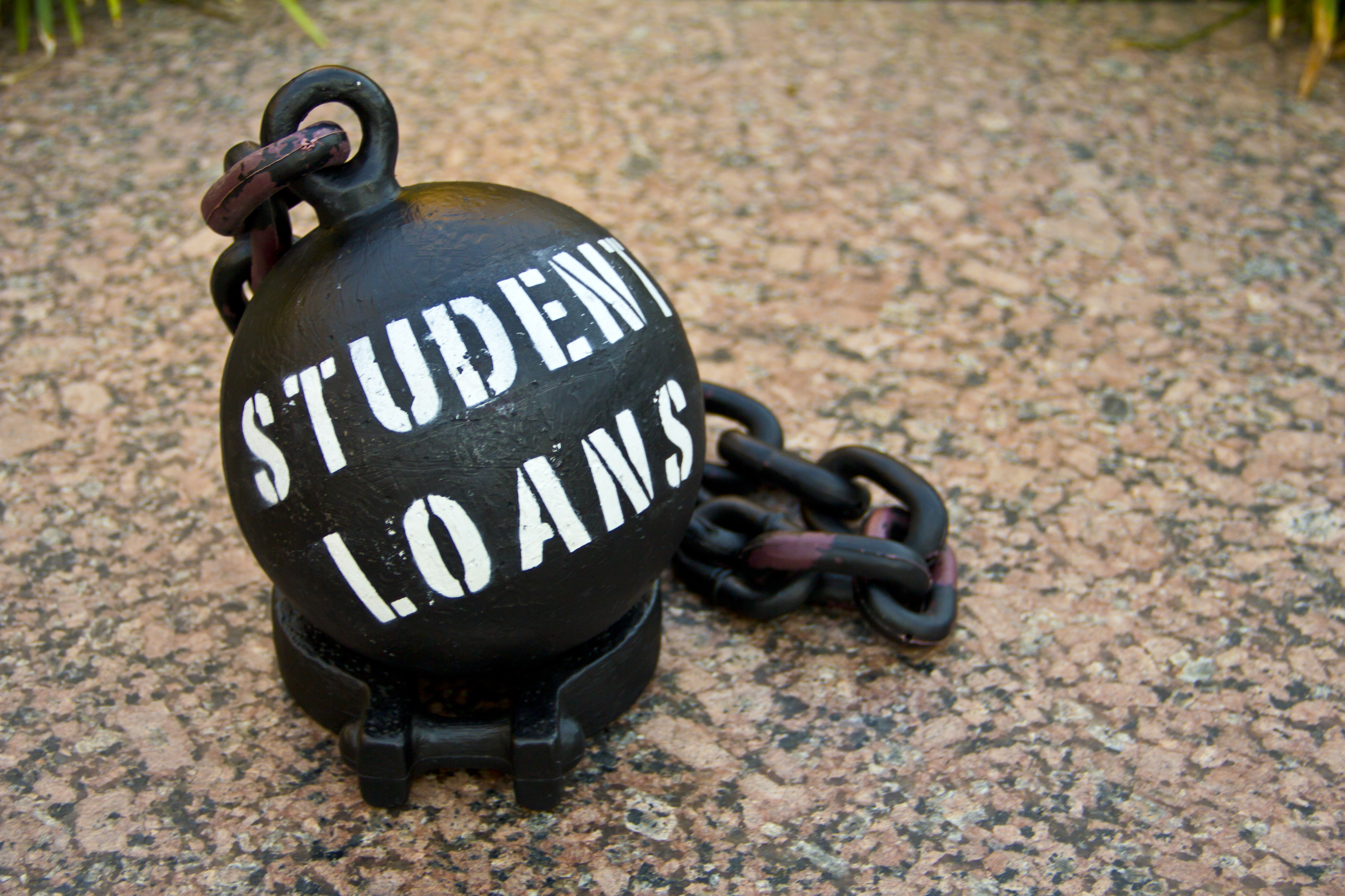 A black ball and chain is emblazoned with the words “STUDENT LOANS.”